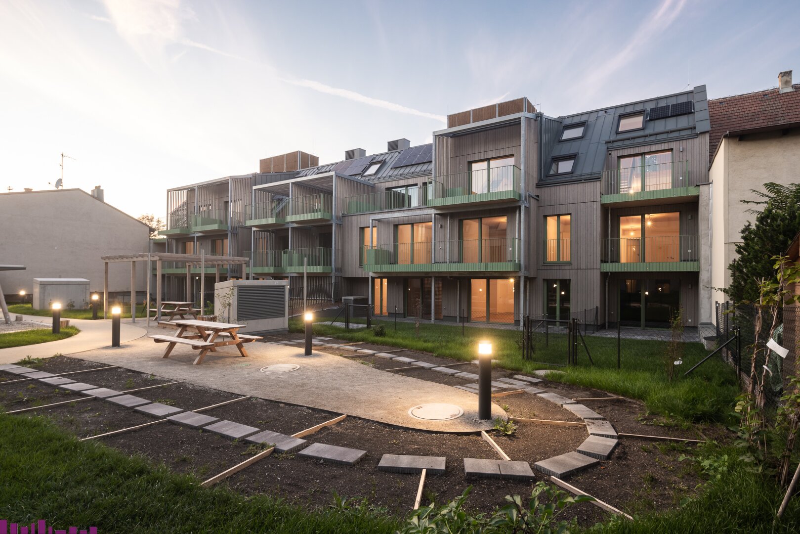 Abendansicht der Wohnhausanlage mit Beeten in der Mitte