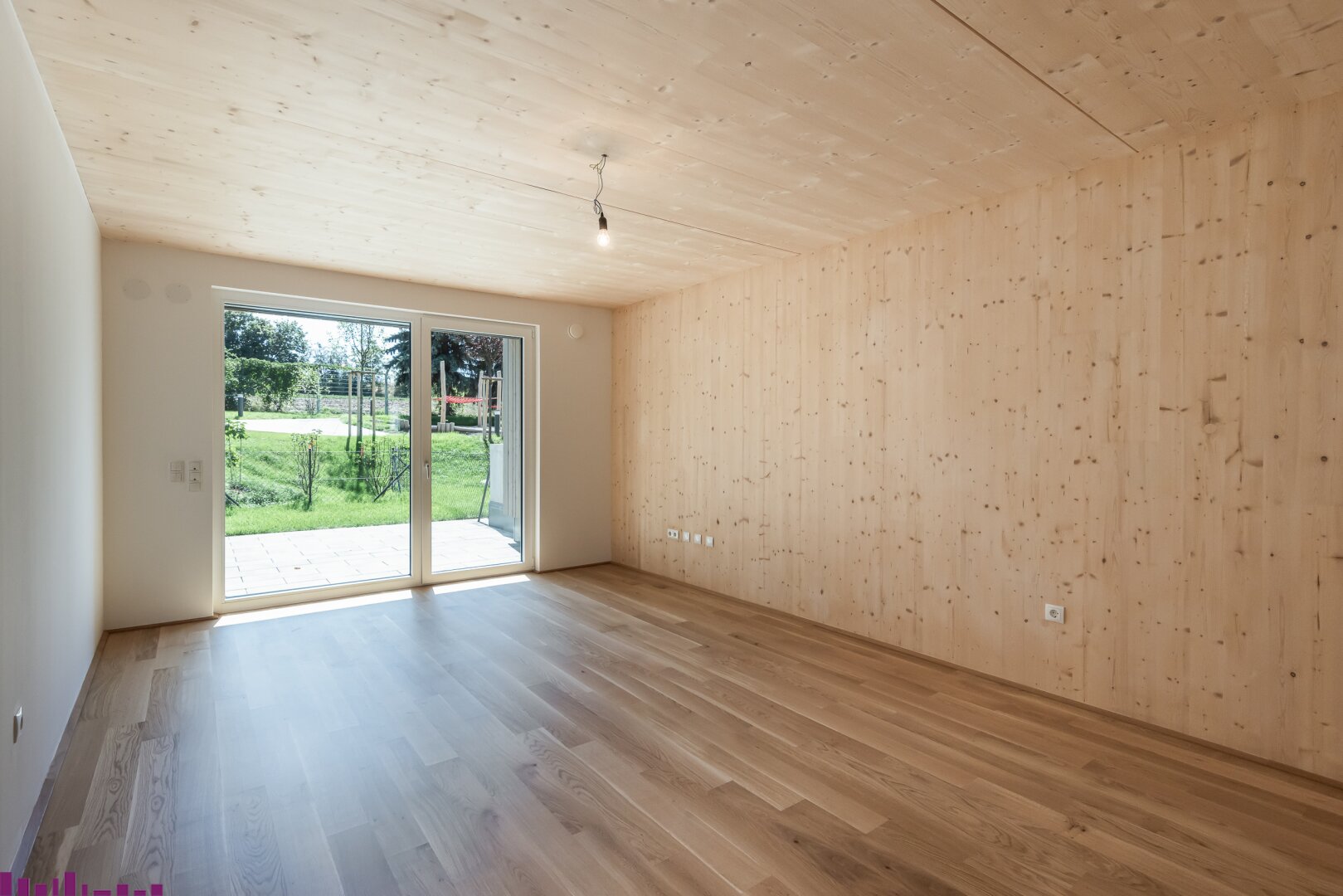 Wohnzimmer mit Blick in den Garten, mit Holzboden und Sichtholzwand.
